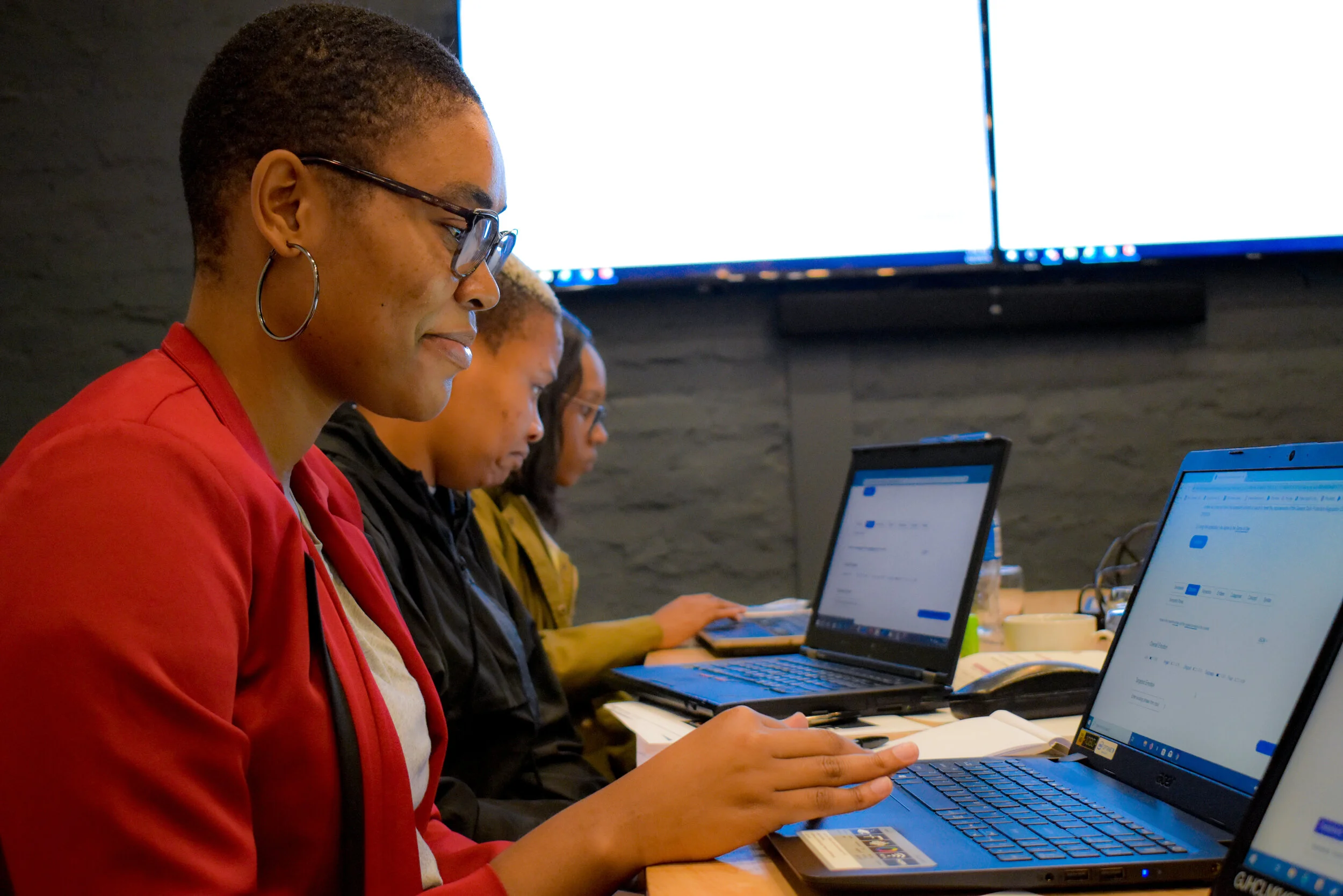 Women working side by side on laptops in a photograph published by WomEng