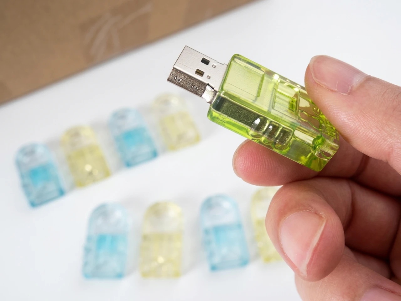 A hand holding a USB connector with a translucent green printed enclosure