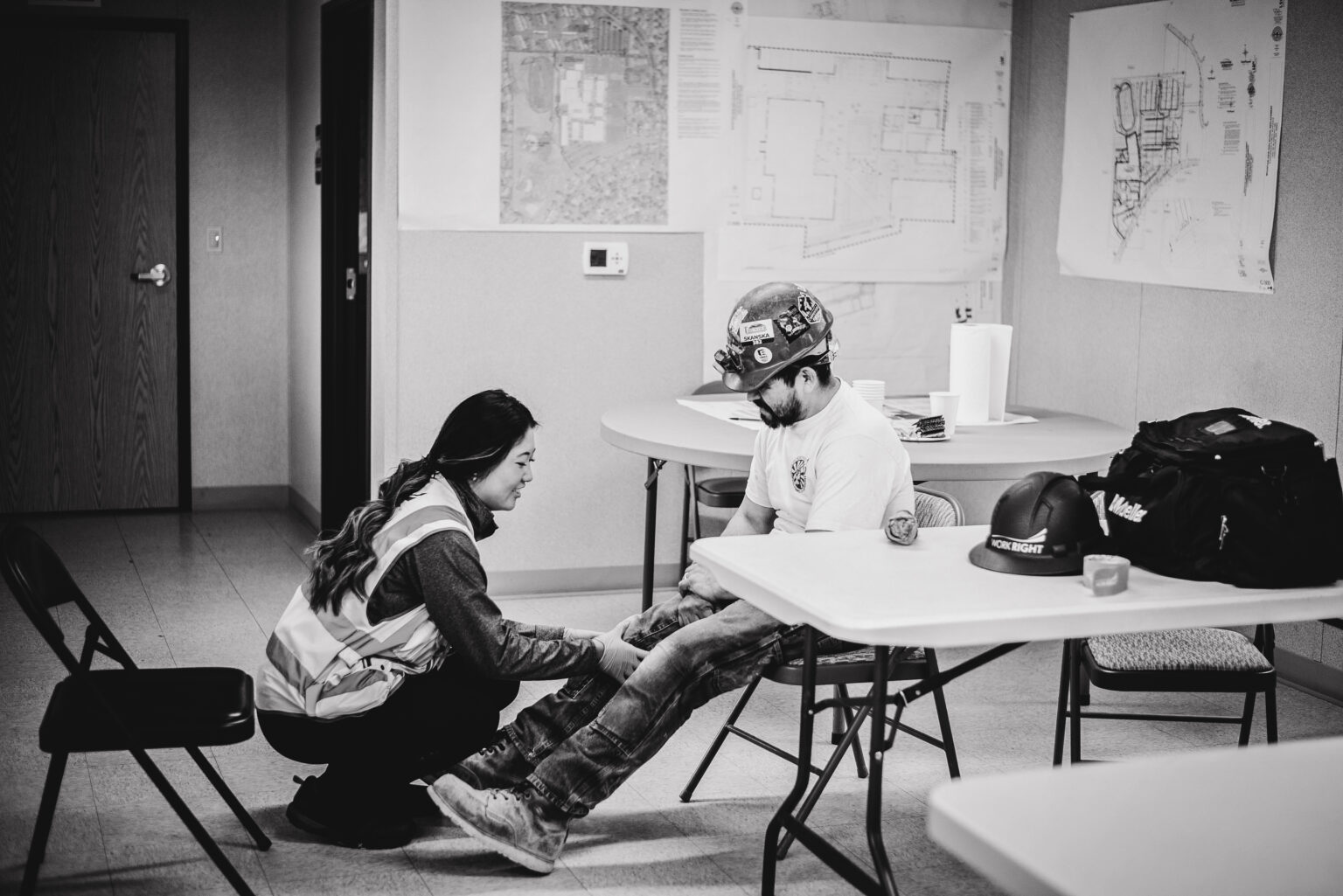 A Work Right clinician examines the knee of a construction worker seated at a worksite