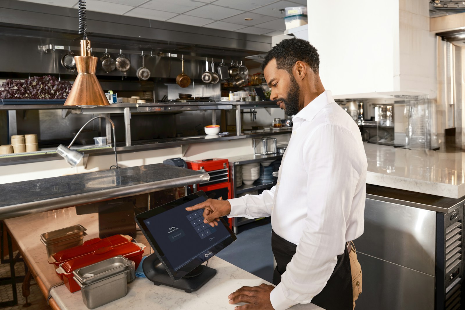 Restaurant employee using a touchscreen terminal at the end of a shift in a commercial kitchen
