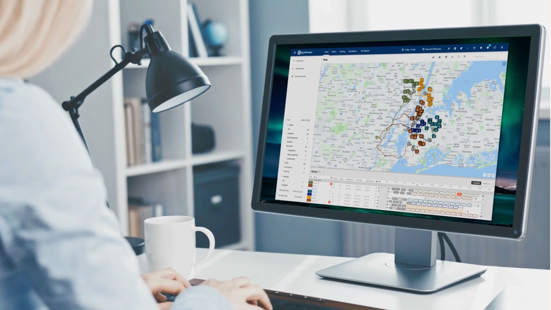 RouteManager marketing photograph showing a desktop map with colour-coded routes and delivery stops