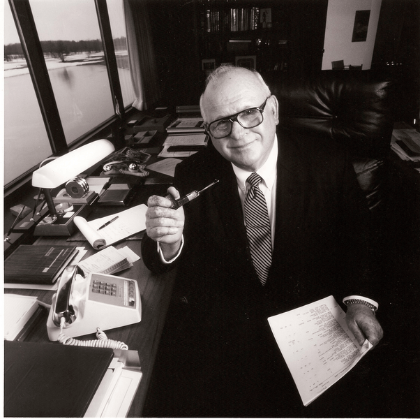 Founder John H. McConnell seated at his desk, holding a pipe