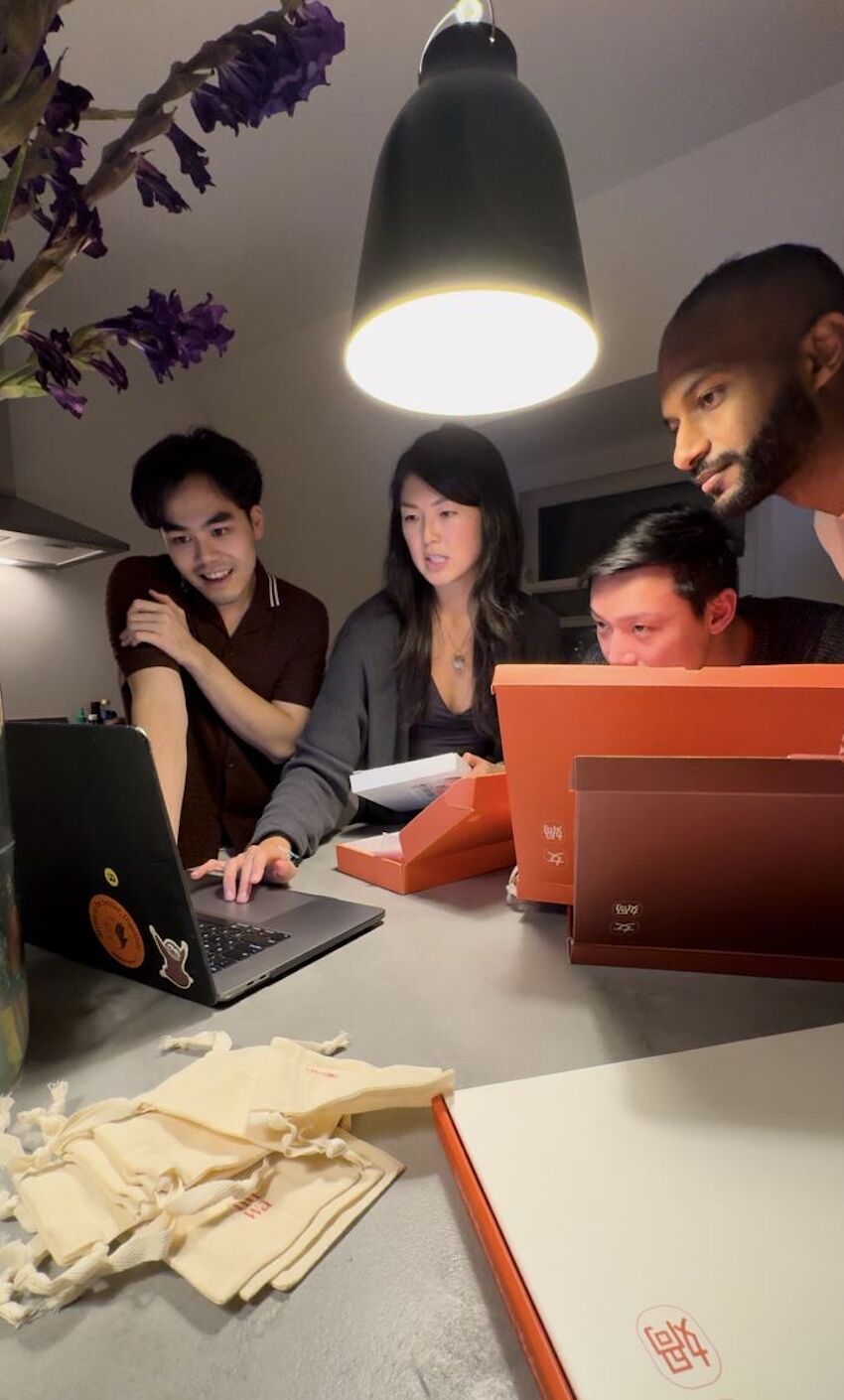 A group gathered around a laptop on a kitchen counter in a candid photograph shared by Wye Yew Ho
