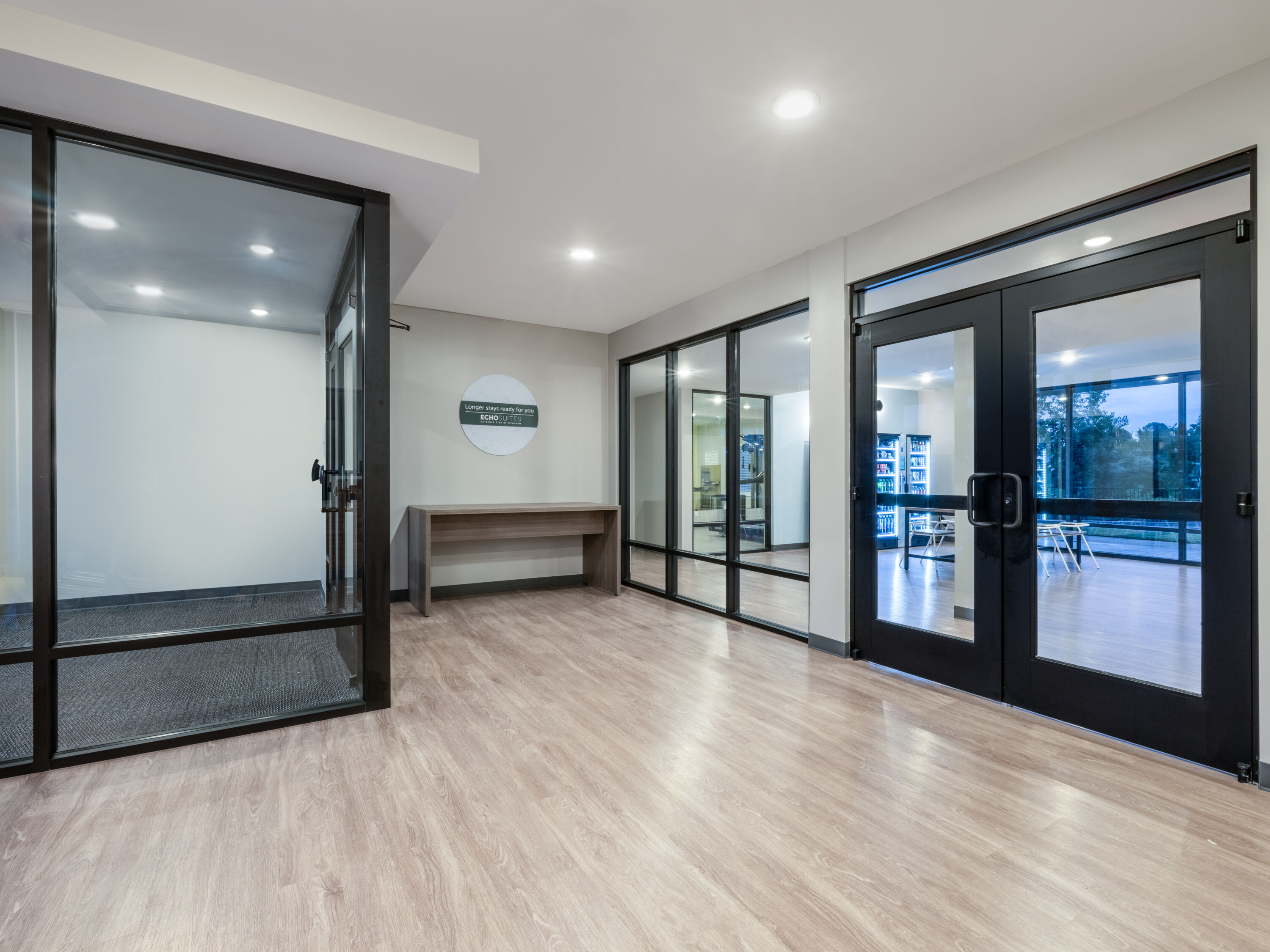 ECHO Suites Spartanburg lobby with glass doors, light wood flooring and a longer-stays sign