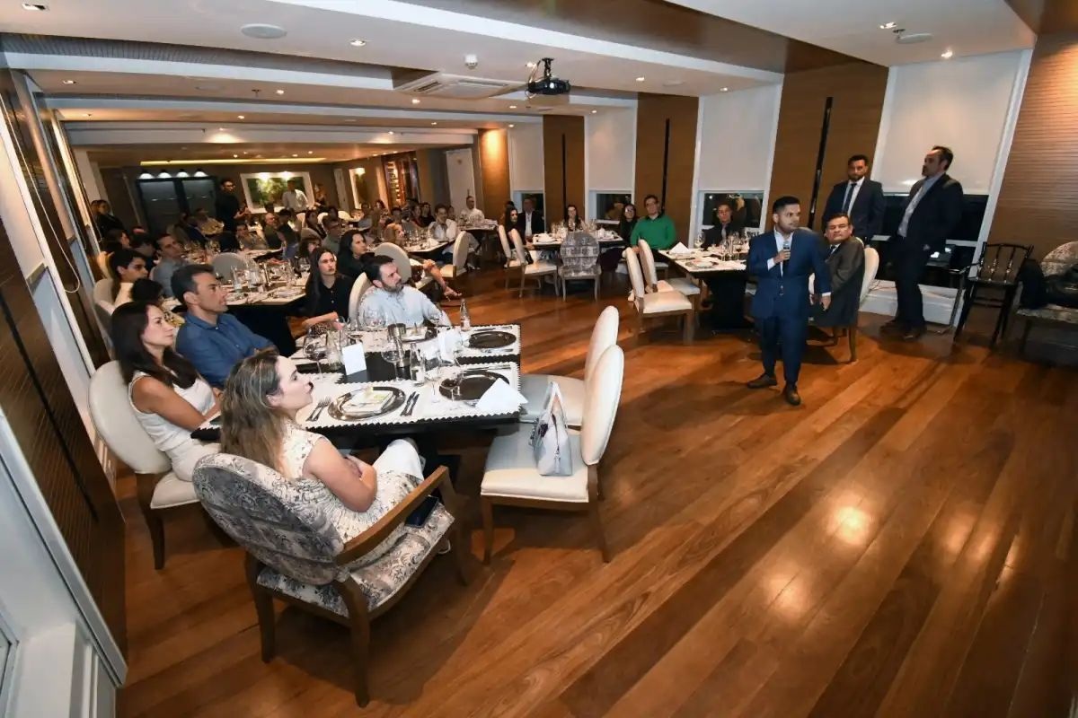 Businesspeople seated around dinner tables during an international investment event in São José dos Campos