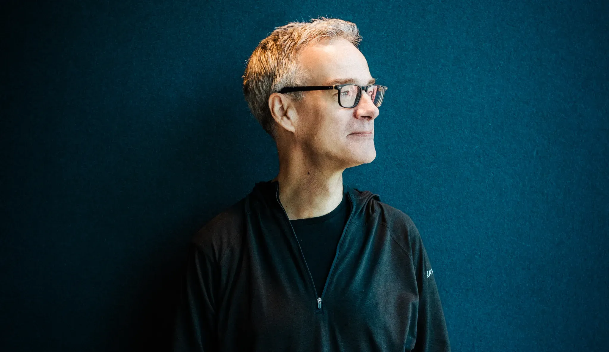 XBOW founder Oege de Moor wearing glasses, photographed against a dark teal background