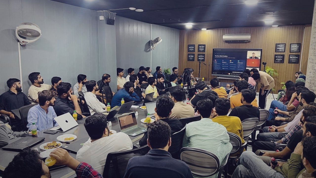 Xeven team gathered around laptops and a presentation screen for a learning session