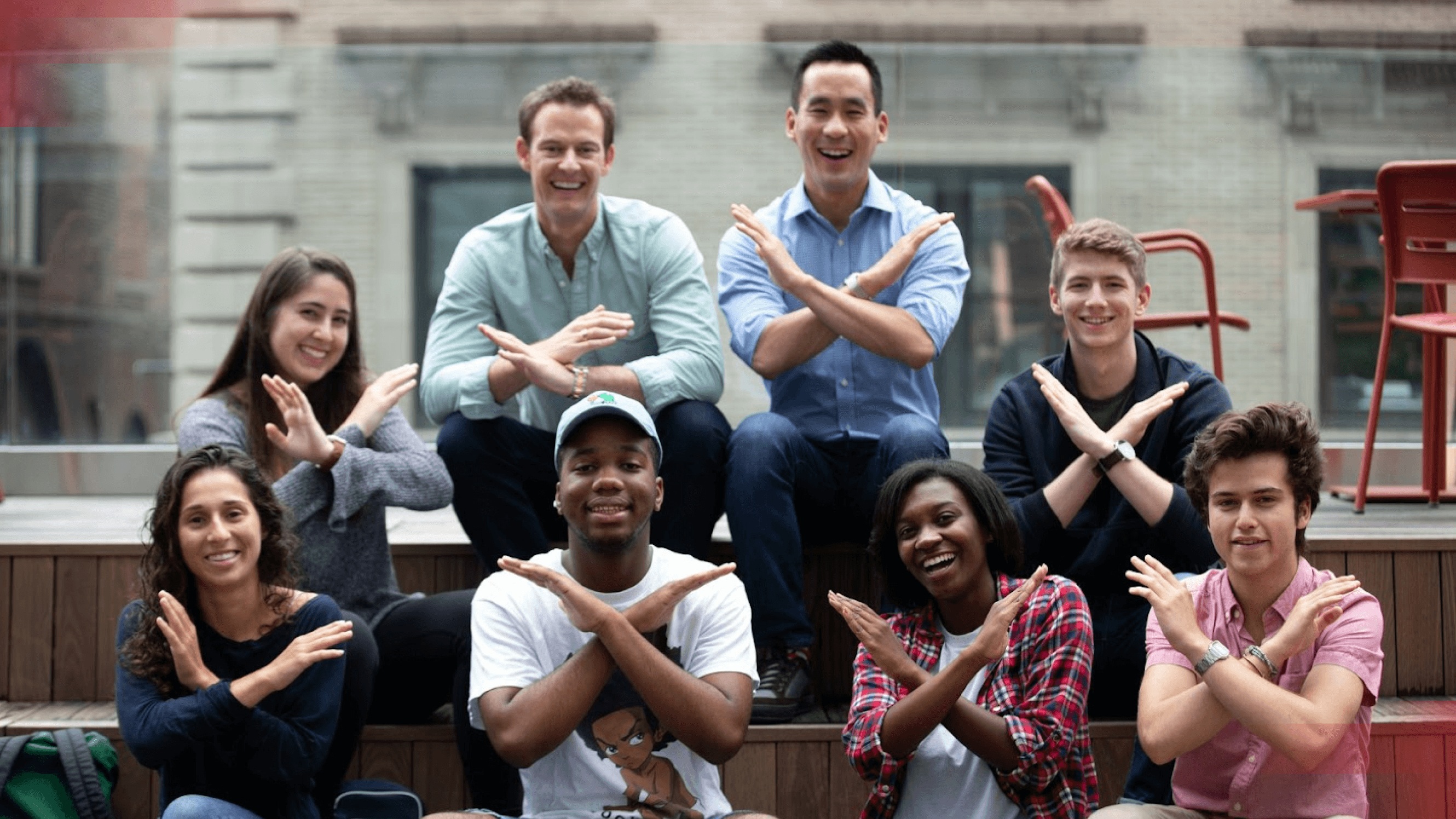 Xfund team members and fellows seated together outdoors, crossing their arms into X shapes.