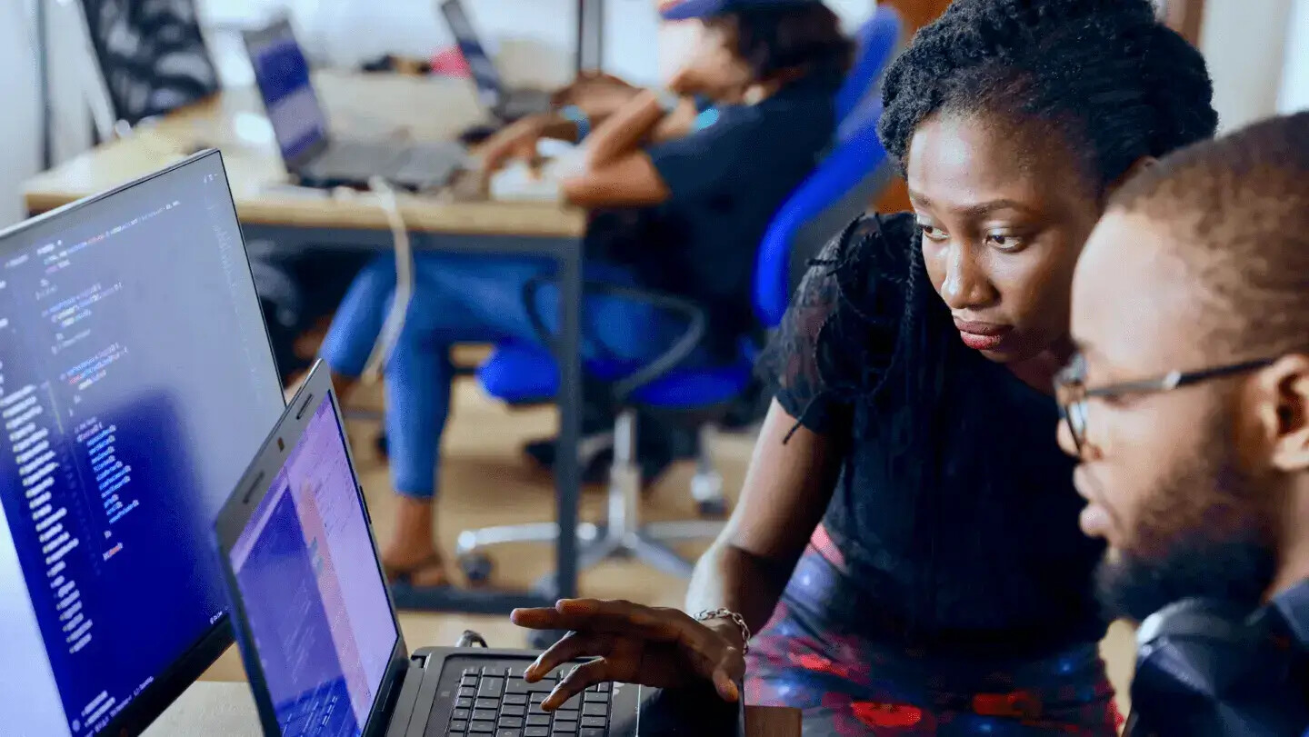 Two technology workers reviewing code together at computers