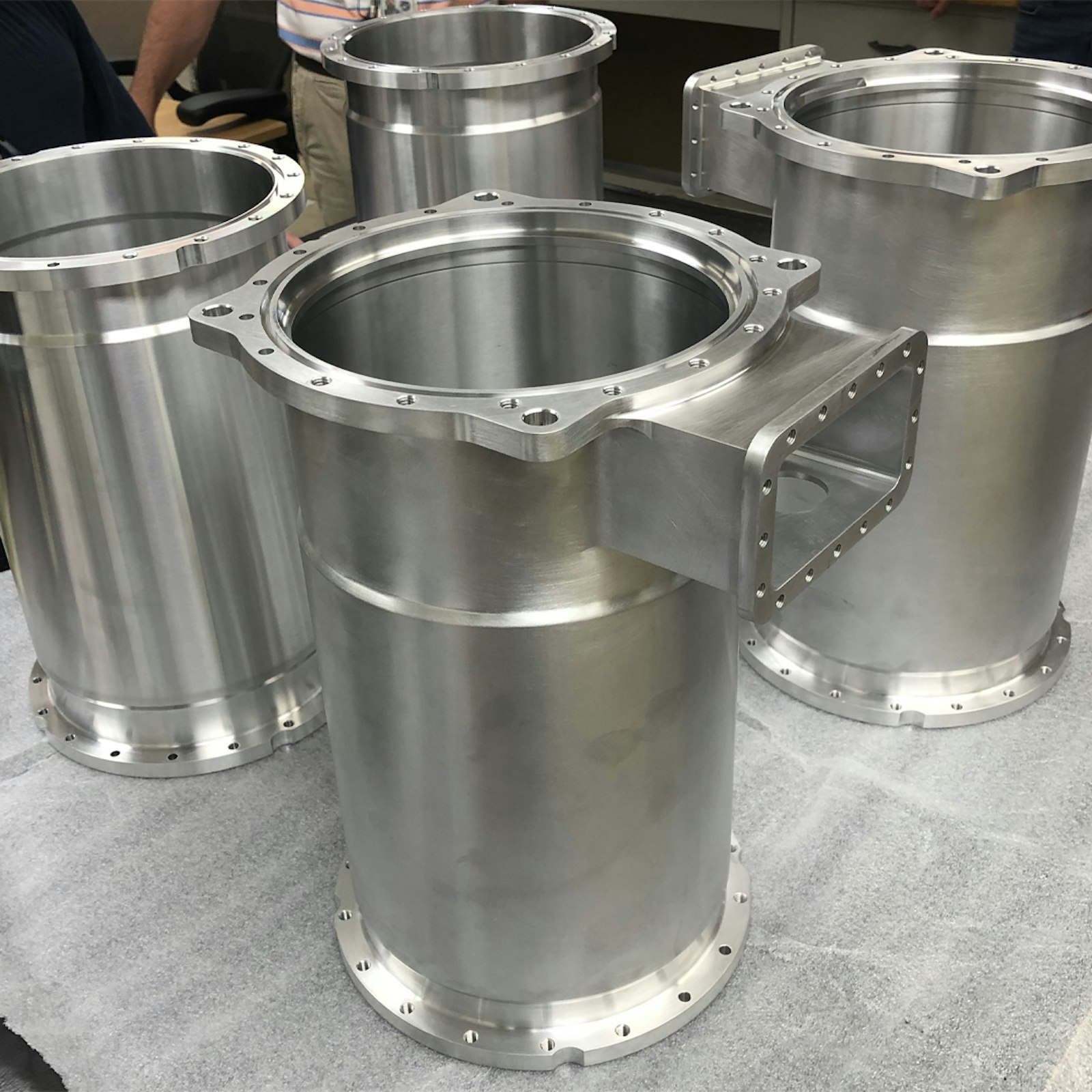 Four cylindrical machined aluminum vessel components for NASA’s air purification system.