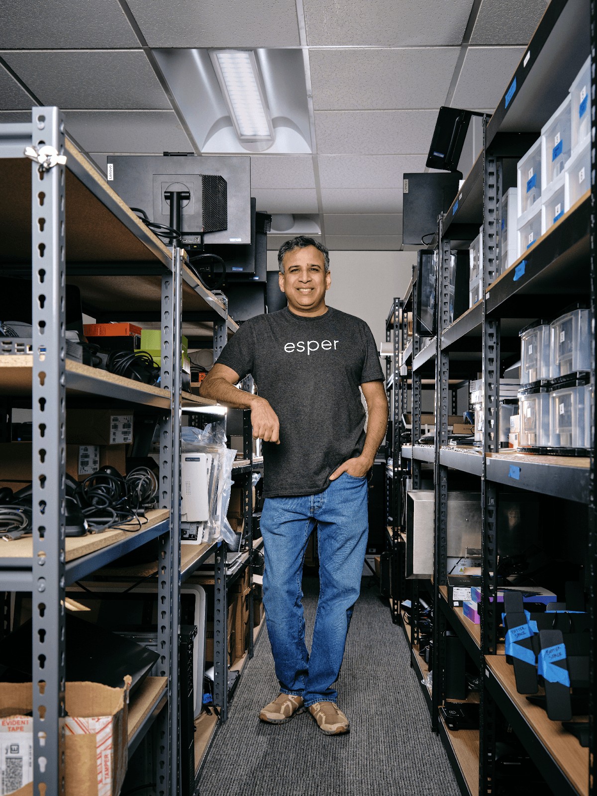 Yadhu Gopalan standing between shelves of computers and test devices in Esper's hardware lab