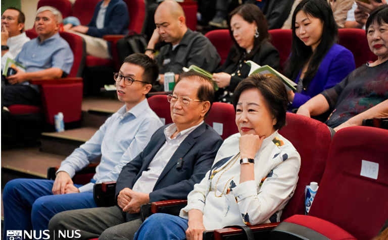 Yao Hsiao Tung seated among attendees in a red-seated university auditorium