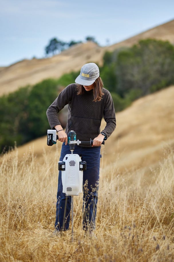 A field technician operating Yard Stick soil measurement equipment in dry grassland