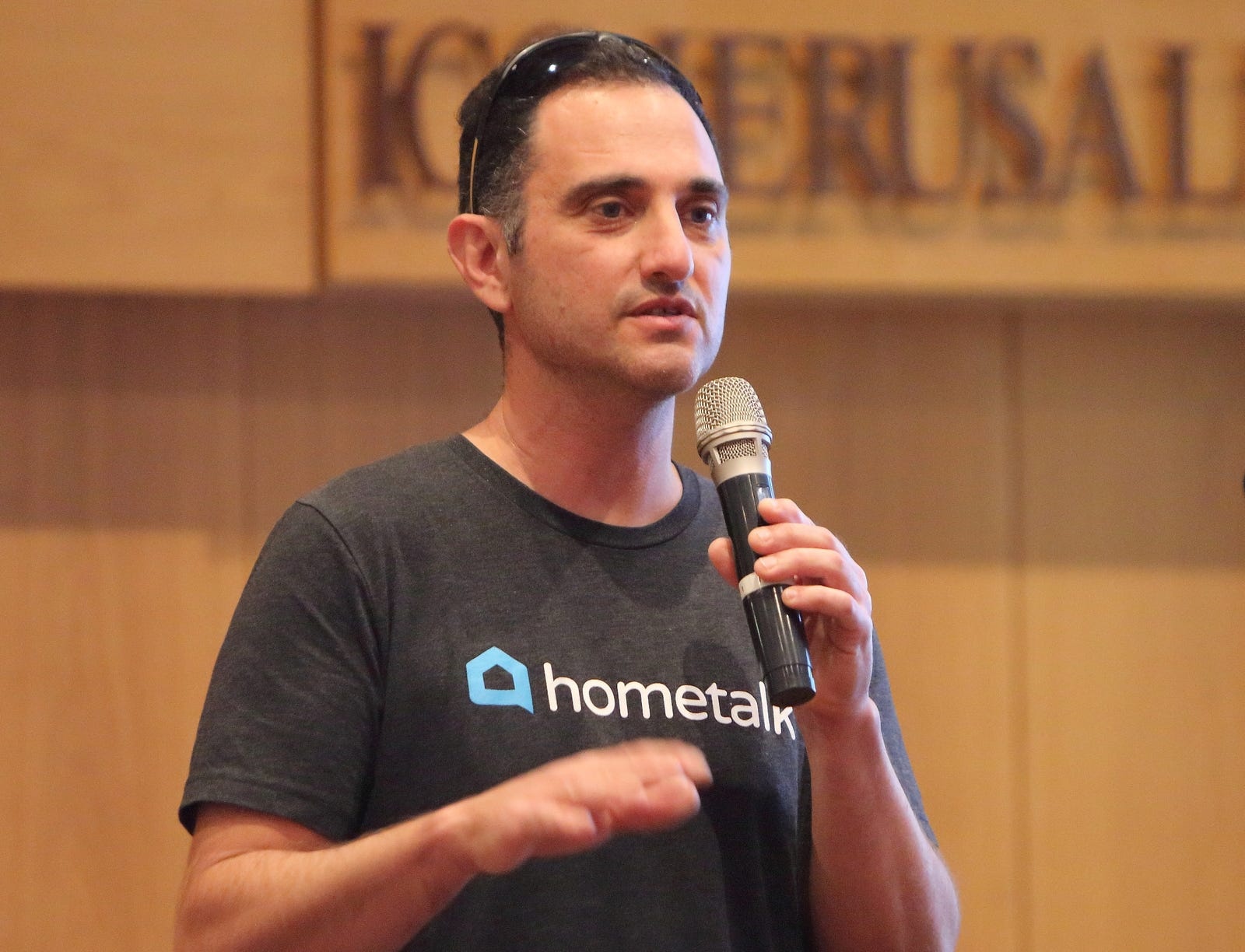 Yaron Ben Shaul speaking into a handheld microphone in a Hometalk T-shirt