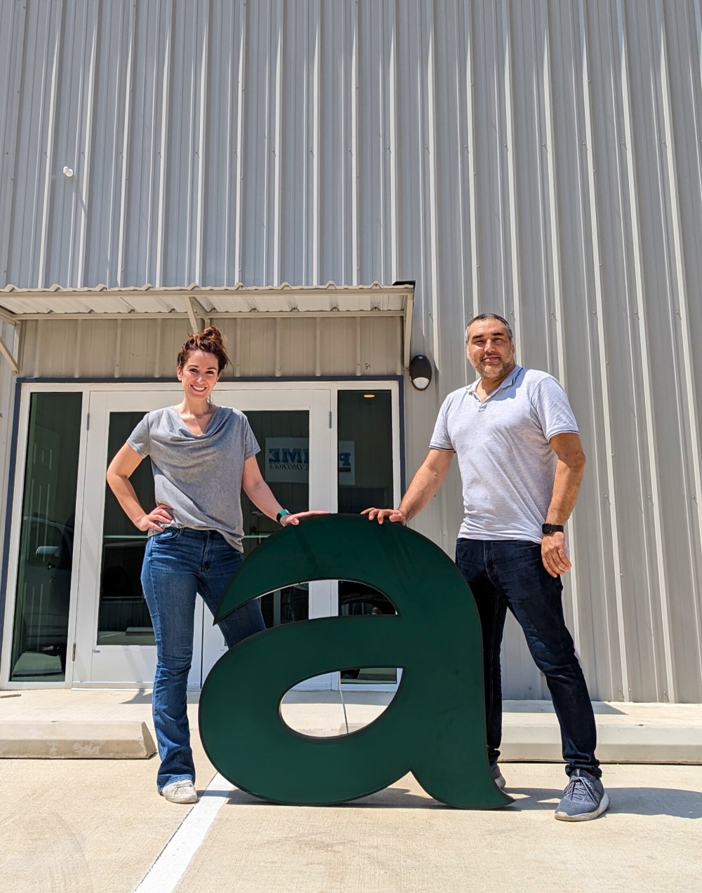 Farrah and Yassin Sibai standing outside an Afia facility with a large lowercase letter a
