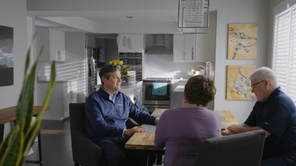 A Yes Hearing specialist sitting with two adults at a kitchen table