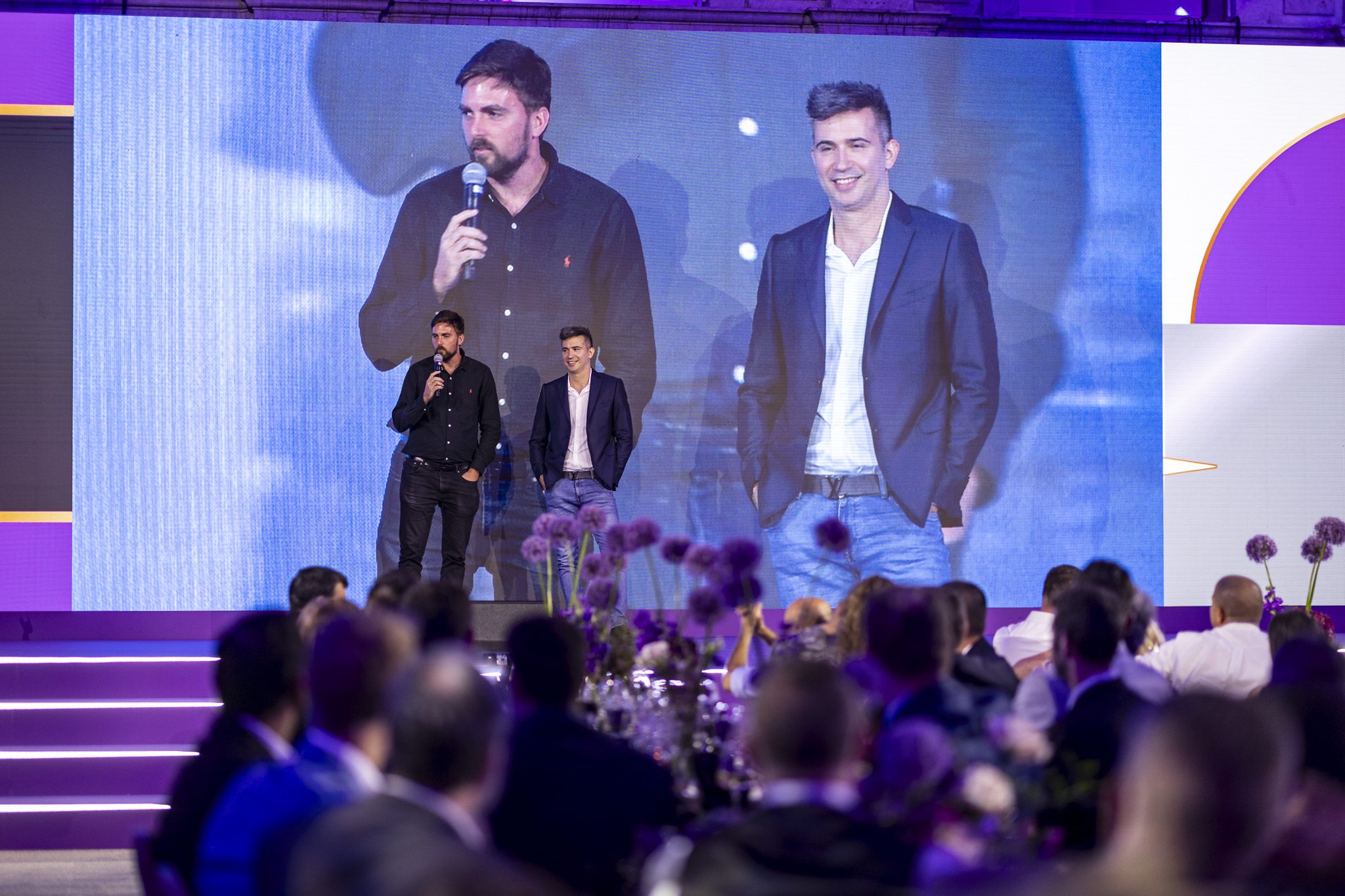 Nadir Izrael holding a microphone beside Yevgeny Dibrov on stage