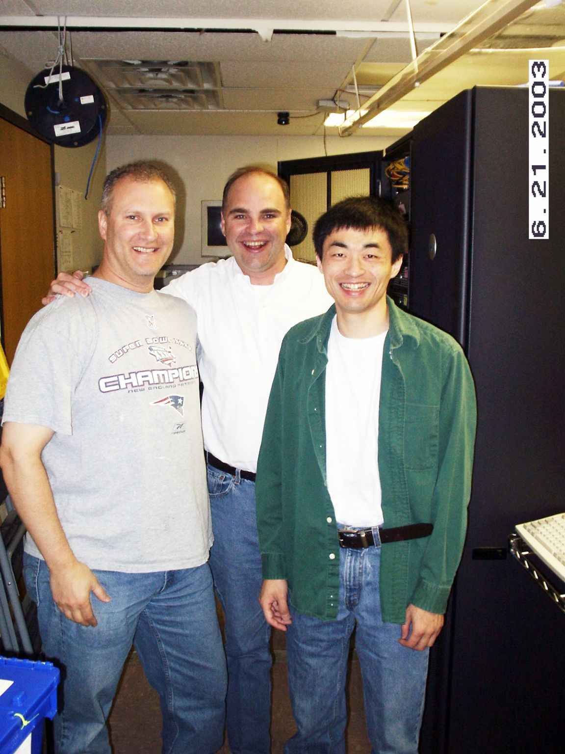 Archival Salary.com team photograph with Yong Zhang at right, standing beside server cabinets with two colleagues.
