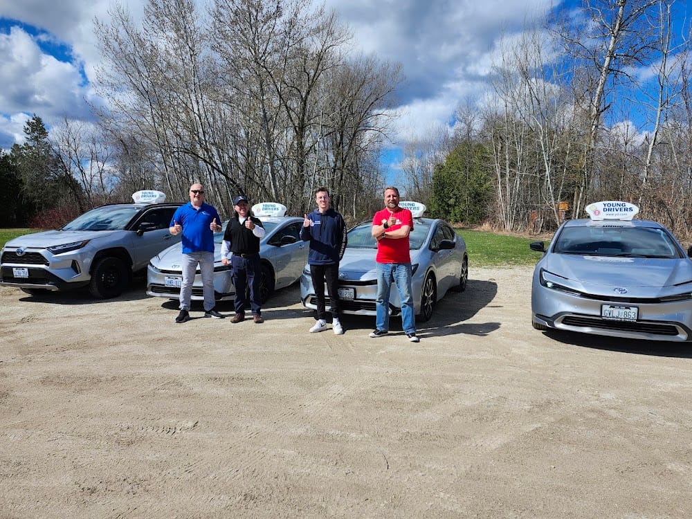 Young Drivers instructors standing beside branded training cars