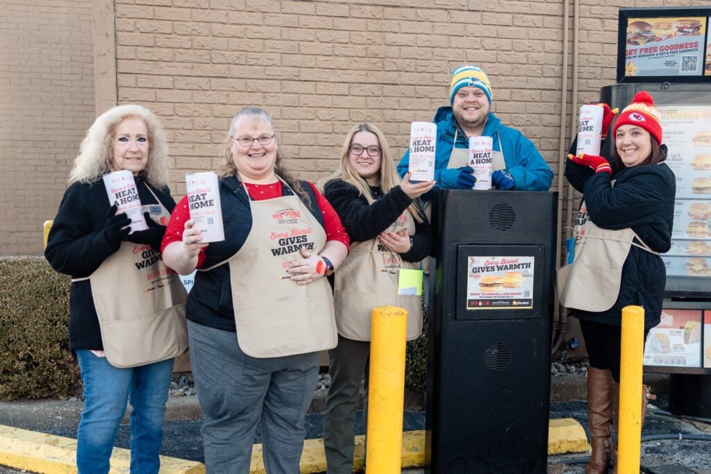 Five volunteers in winter clothing and charity aprons at a Heat Up St. Louis event, pictured in Busey Bank’s customer story