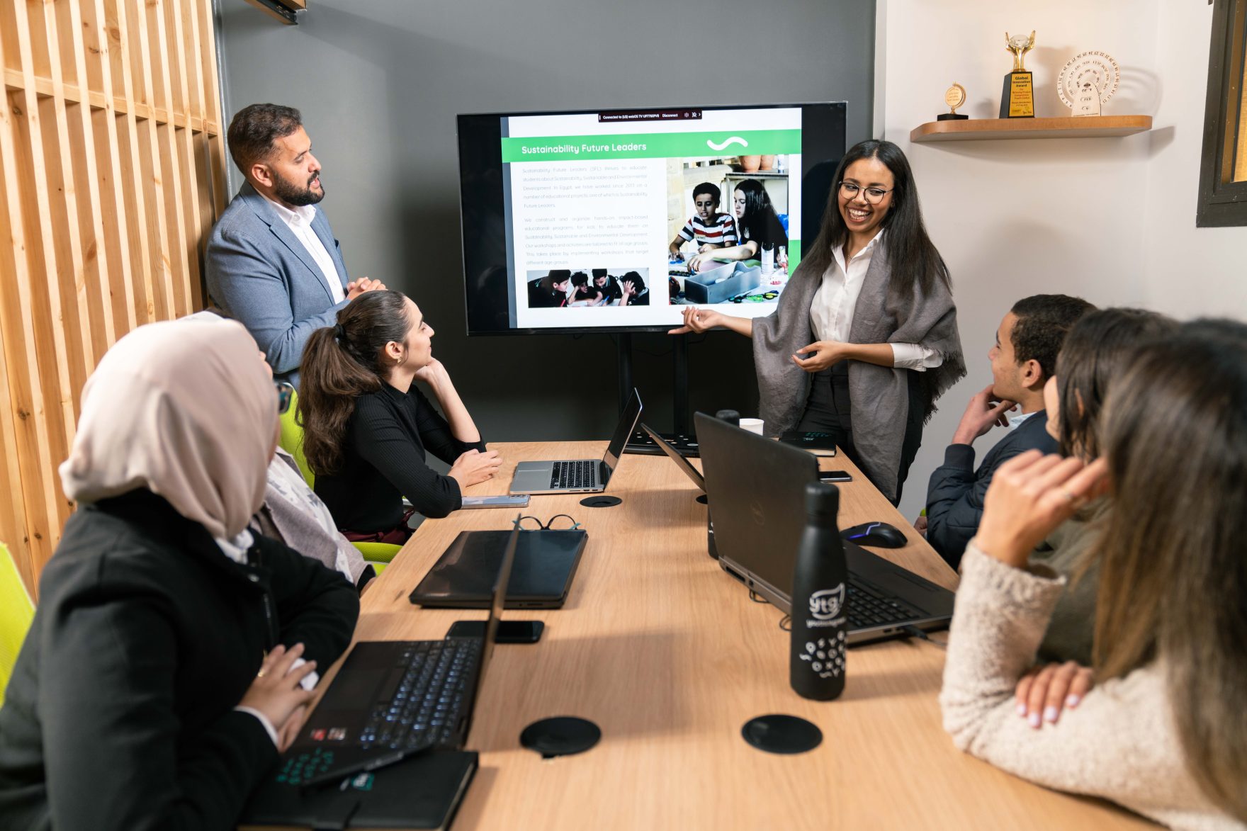 A group gathered around a meeting table during a presentation about Sustainability Future Leaders