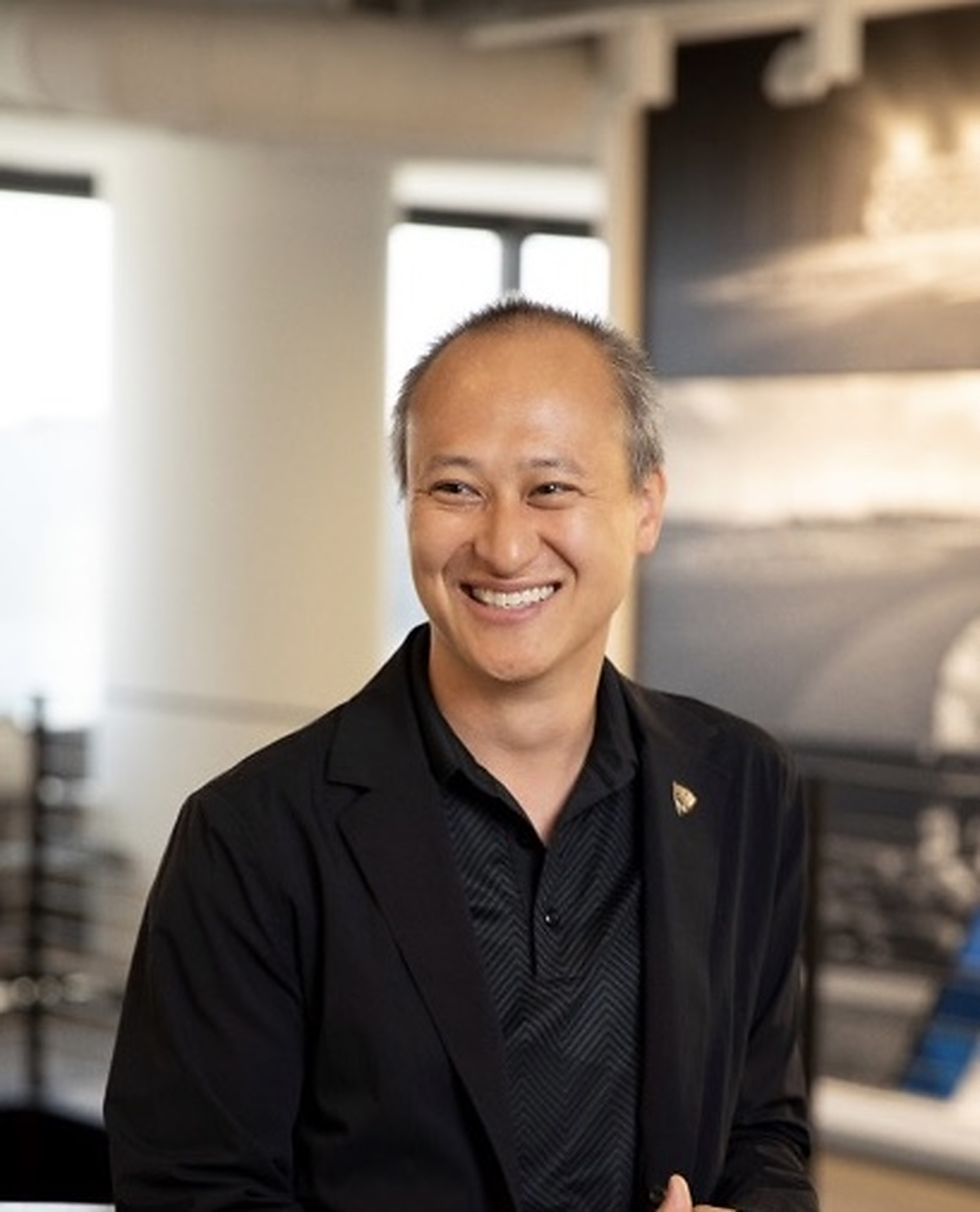 YuChiang Cheng smiling in a black jacket in an indoor setting