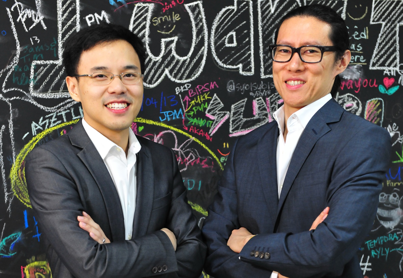 Hann Liew on the left and Yuen Tuck Siew on the right, standing before a colourful chalkboard
