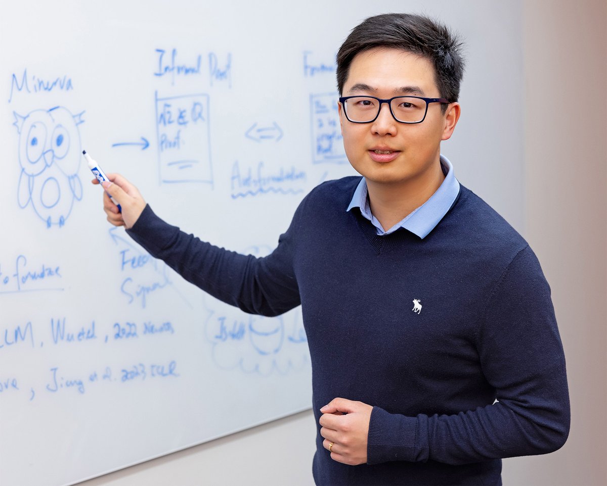 Yuhuai Tony Wu points to a Minerva drawing and reasoning diagrams on a whiteboard