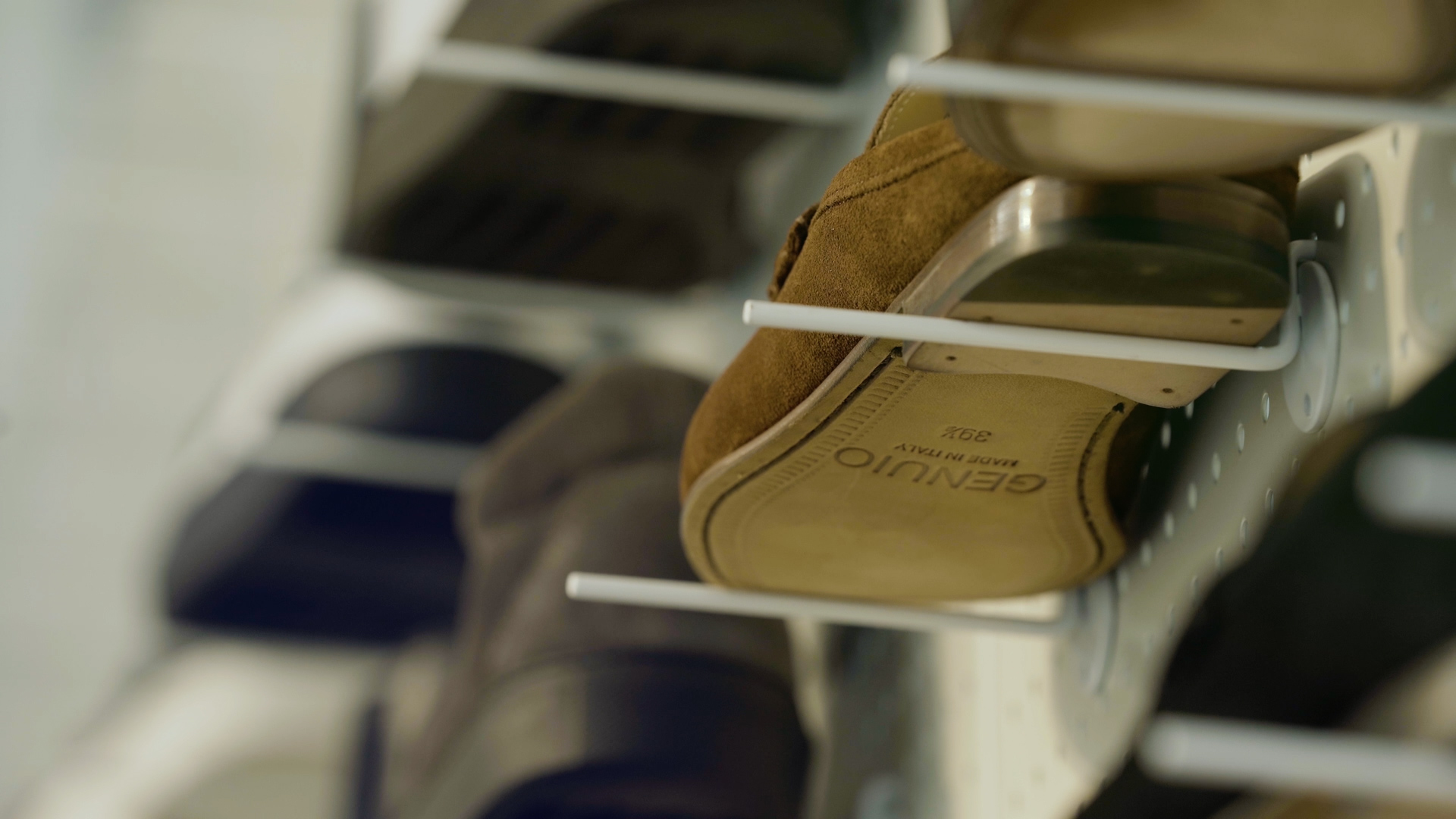 A Genuio suede shoe moving along a factory production rack