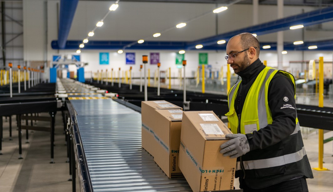 A Movianto warehouse worker guides labelled cartons along a roller conveyor