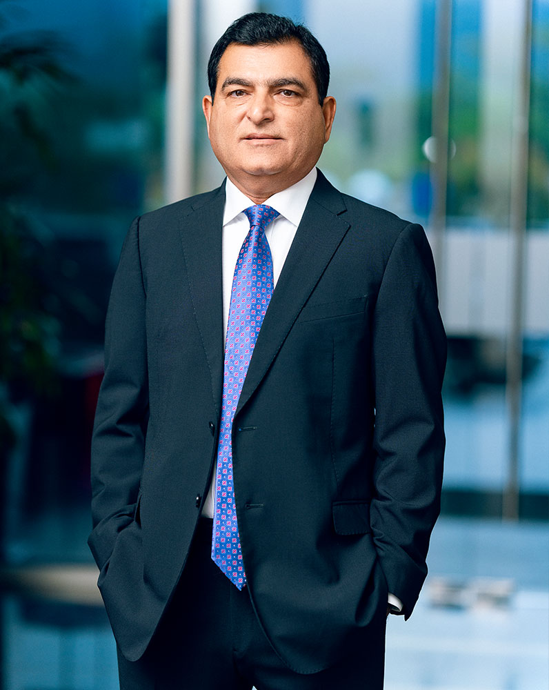 Yusuf Amdani standing in a dark suit and blue patterned tie