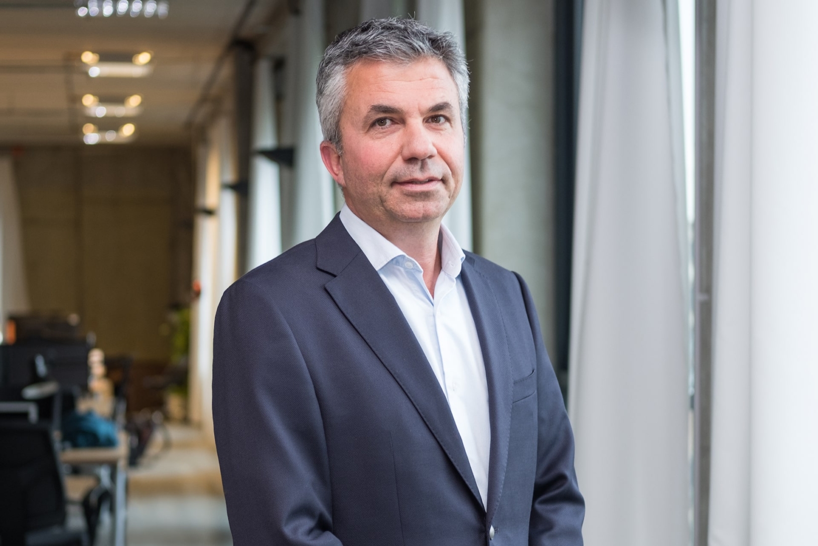 Yuval Ben-Itzhak standing beside windows in a candid office photograph