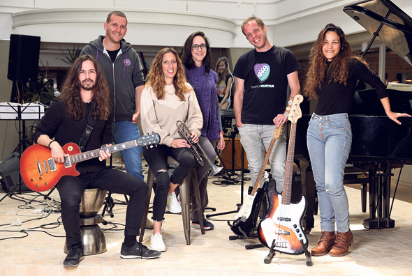 Members of the JoyTunes team pose with guitars, a trumpet, and a piano in 2021