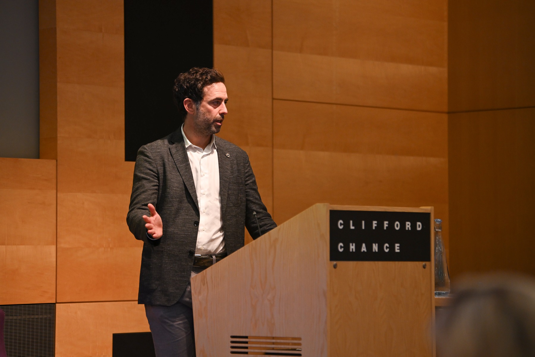 Yuval Rooz speaking beside a wooden lectern at Clifford Chance’s Future of Digital Finance event
