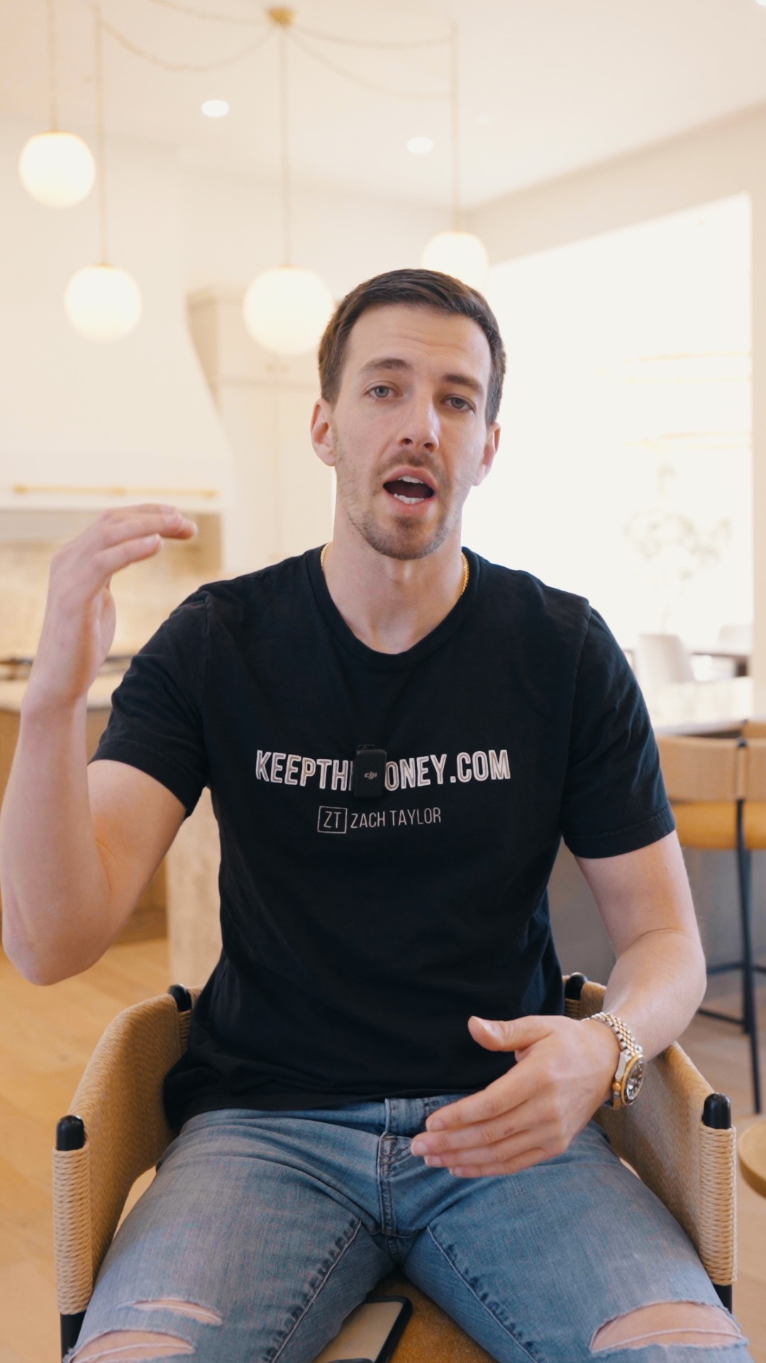 Zach Griest speaks to camera while seated indoors wearing a Keep The Money T-shirt.