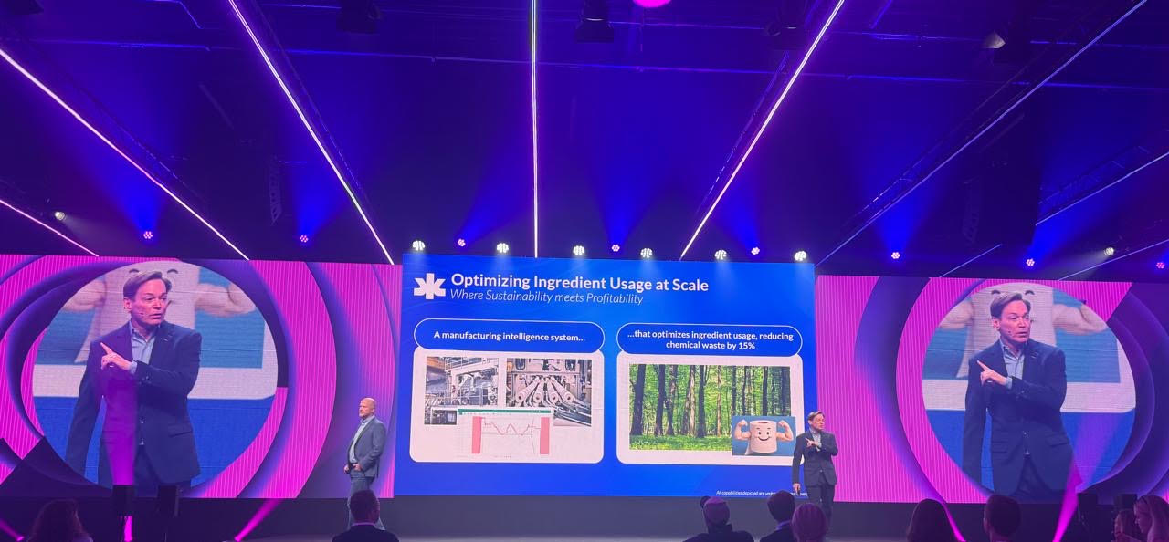 Zack Hicks speaking onstage beside a presentation about manufacturing intelligence