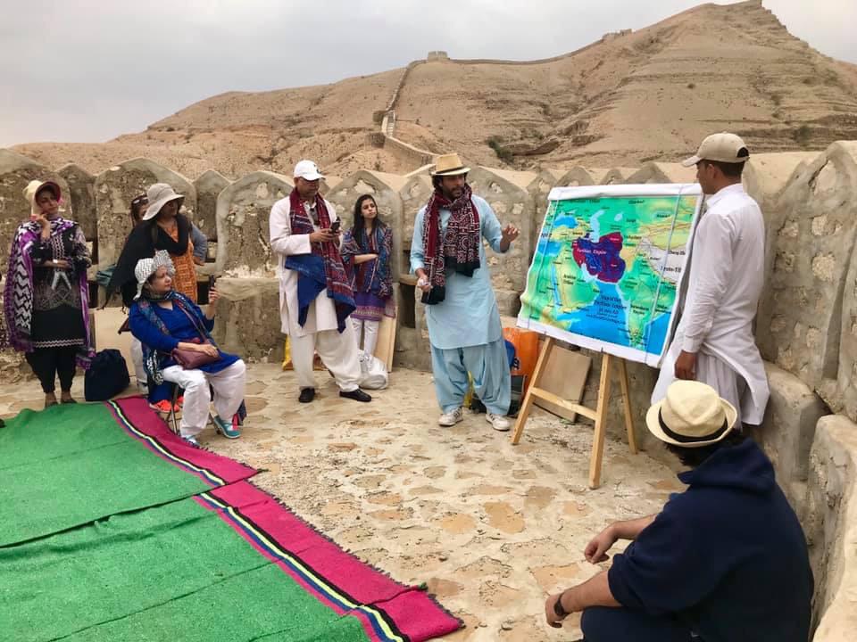 Zain Mustafa teaching a group outdoors beside a large historical map
