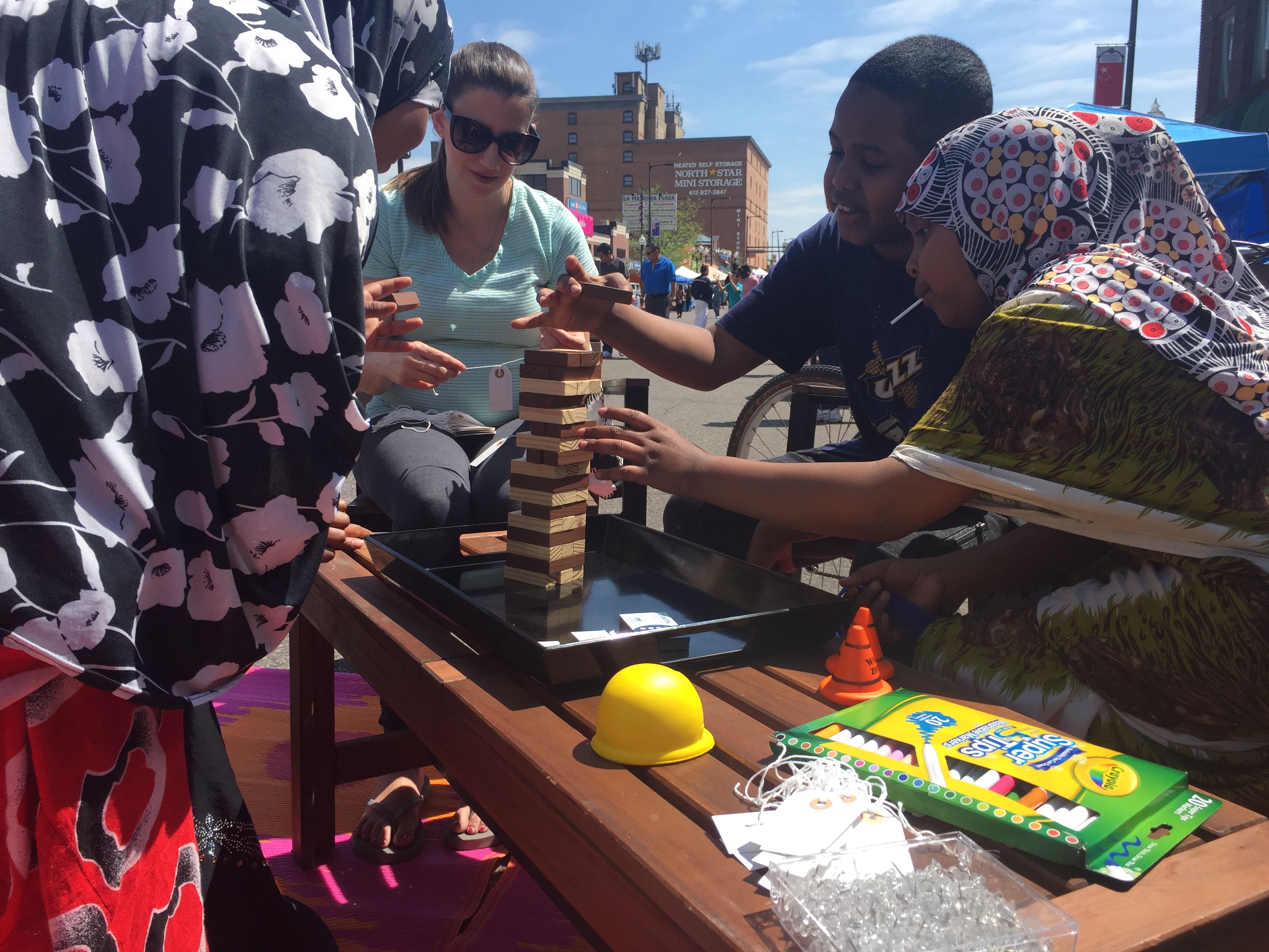 Families playing Jenga at an outdoor outreach table
