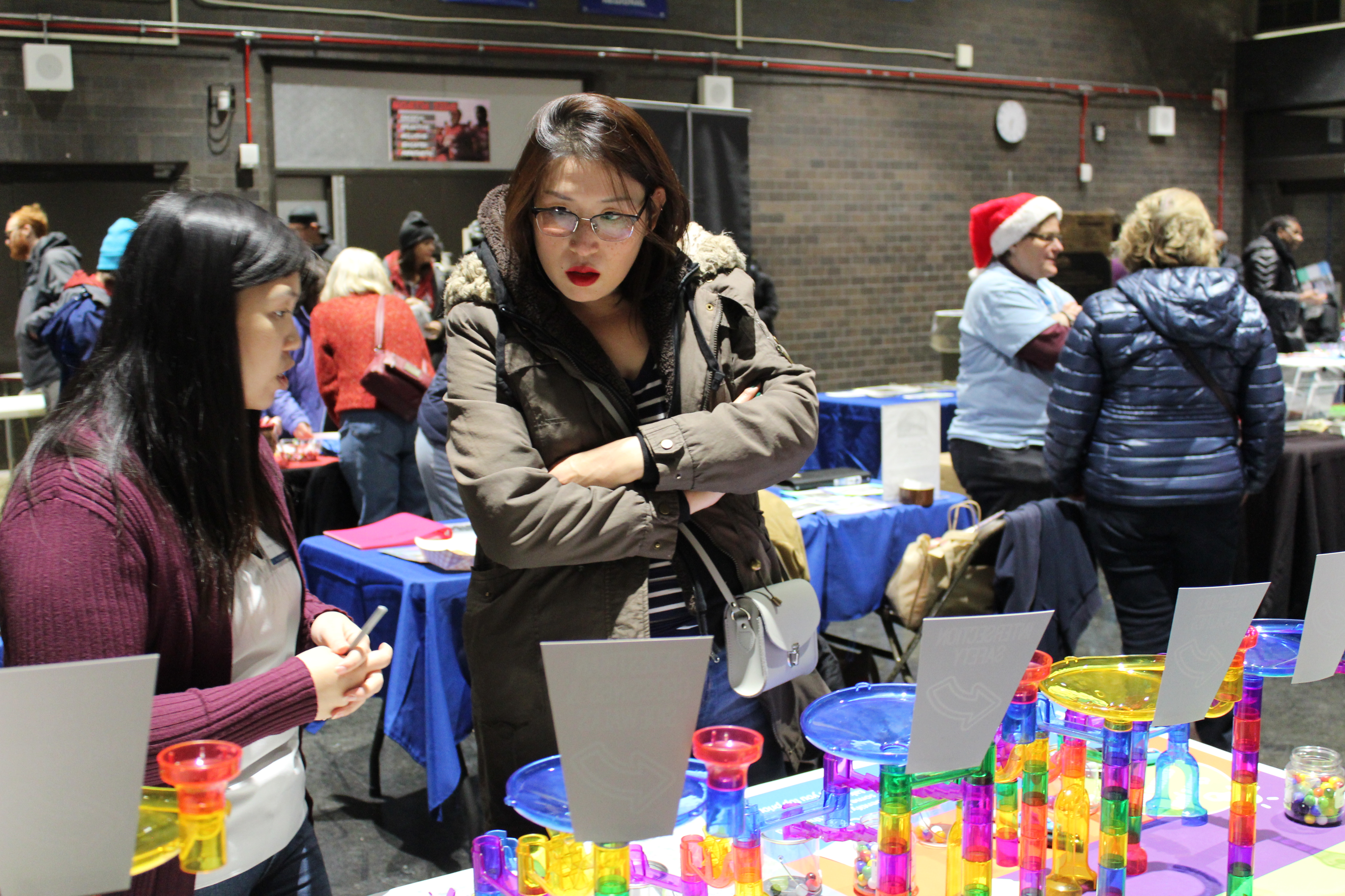Two people discuss a colorful hands-on activity at a crowded community event