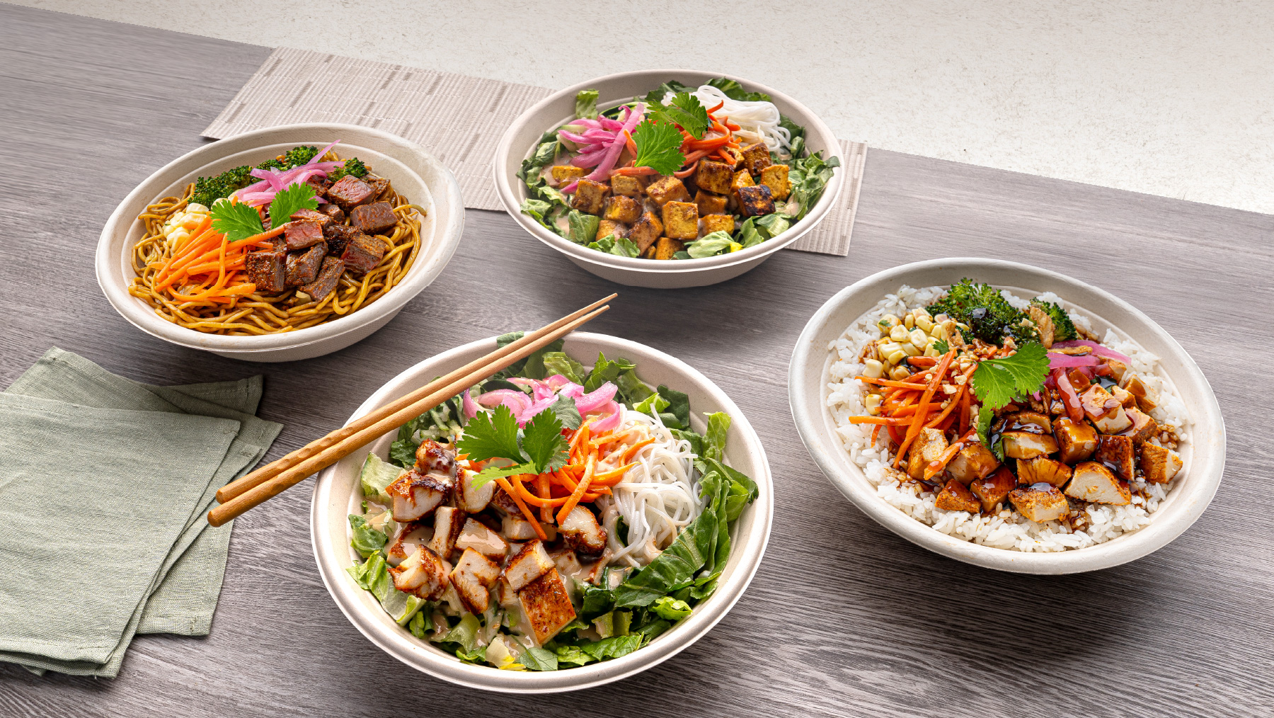 Four Zao bowls with noodles, rice, tofu, chicken and colorful vegetable toppings
