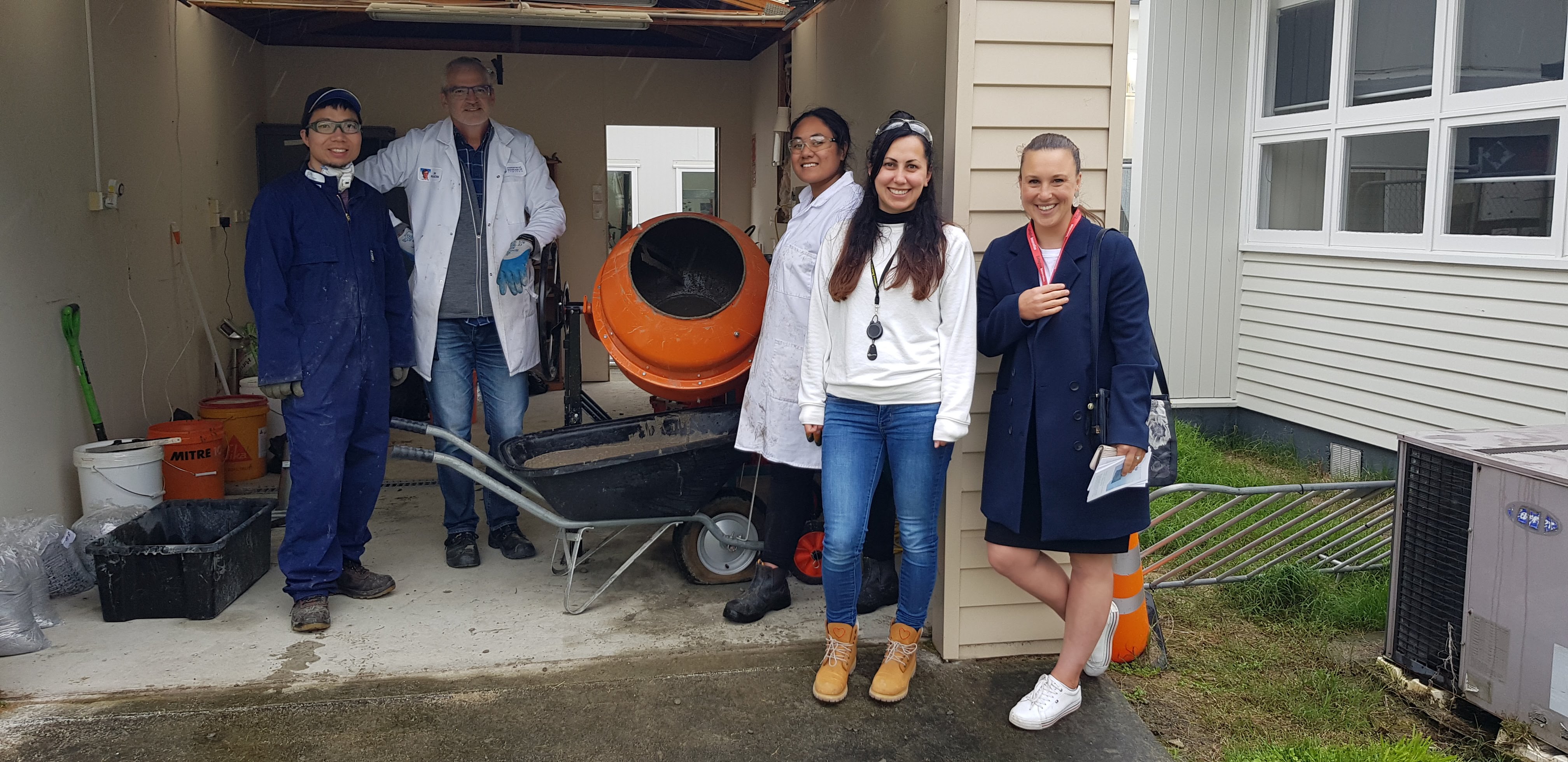 Zarina Alexander with a group beside an orange concrete mixer and testing equipment