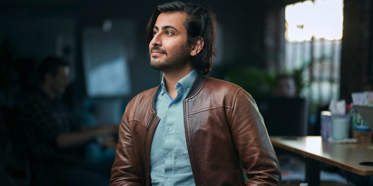Zayd Enam wearing a brown leather jacket in a press photograph