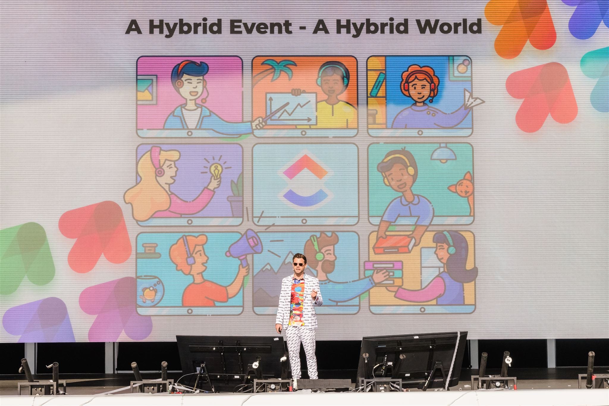 Zeb Evans speaking at ClickUp’s LevelUp 2021 event in a patterned suit before a screen about hybrid work