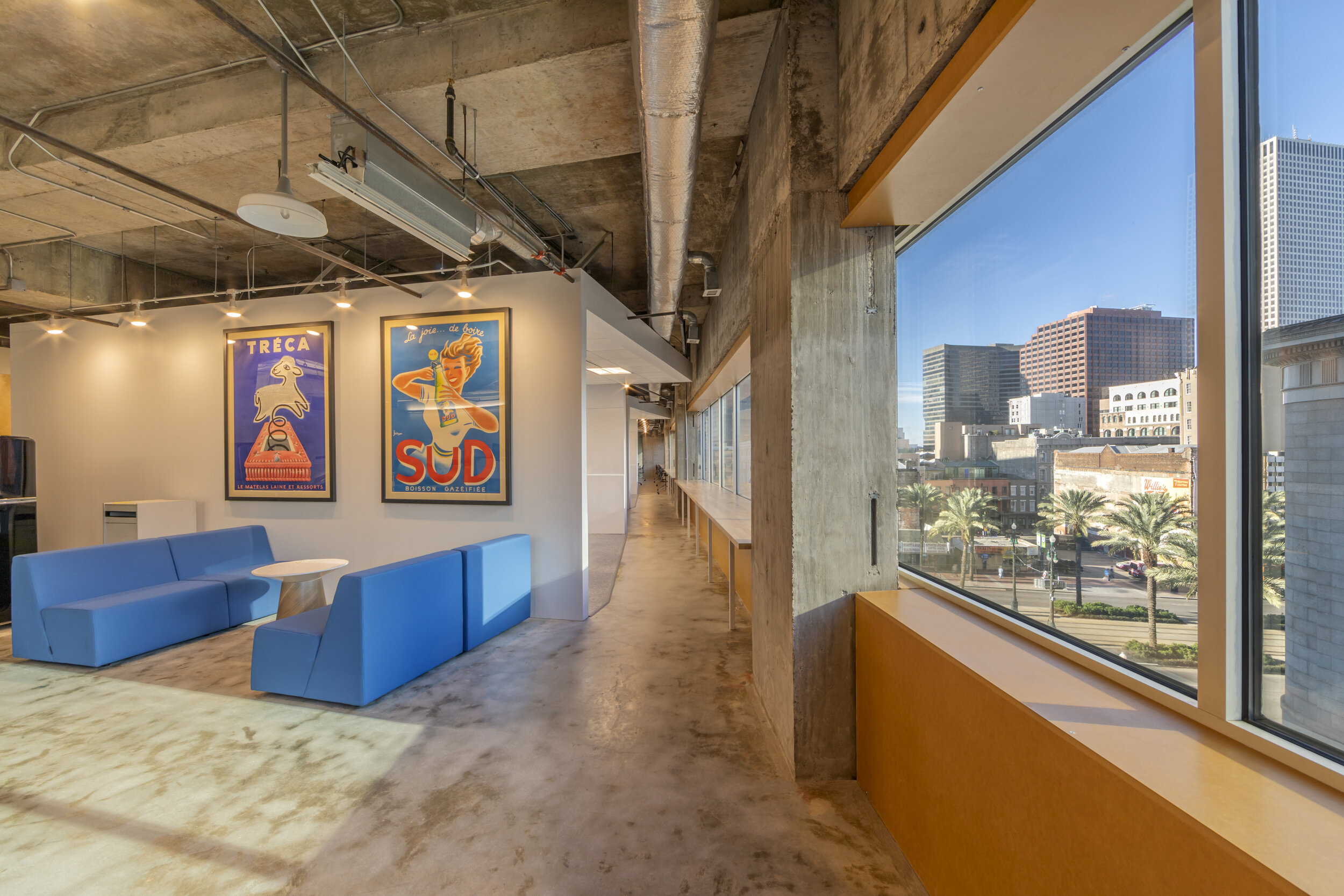 The open-plan Zehnder Communications office in New Orleans, with blue seating, workstations and floor-to-ceiling windows