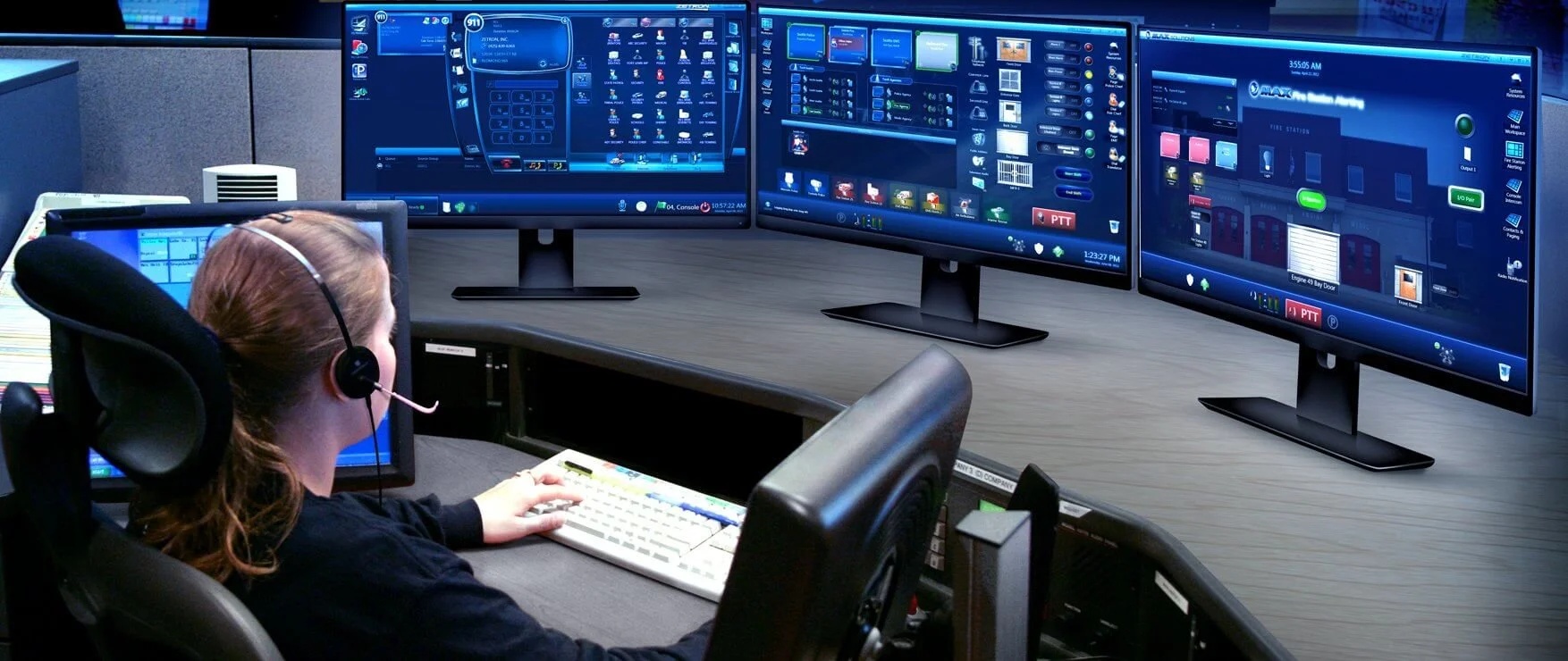 A headset-wearing operator sits at a desk with Zetron call-taking, radio dispatch and fire-station alerting screens