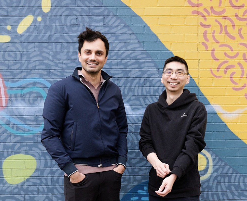 Runpod co-founders Pardeep Singh and Zhen Lu standing in front of a colorful mural