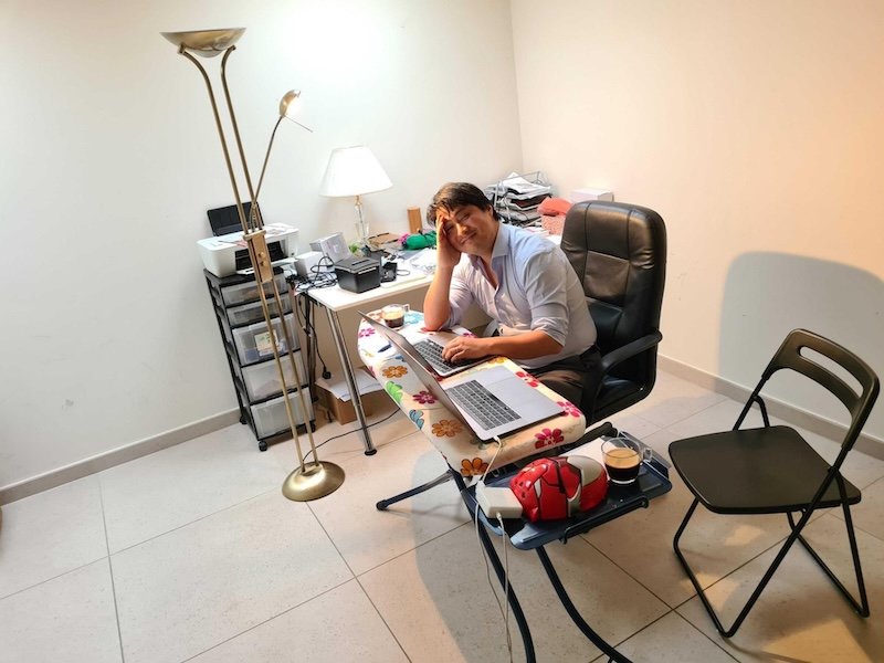 Zhong Xu working on a laptop at an ironing board in a basement office