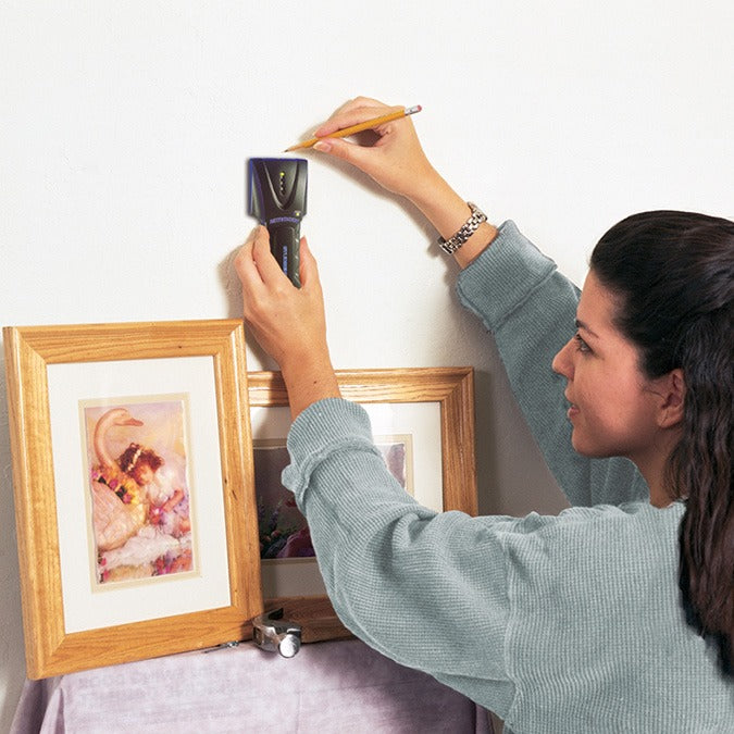 A person using a Zircon SuperScan stud finder against a wall