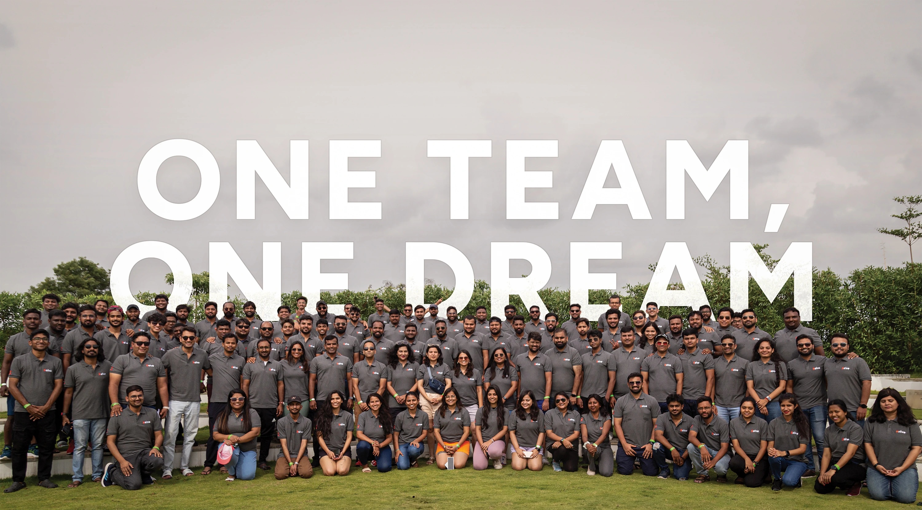 Zolve team gathered outdoors in matching gray shirts