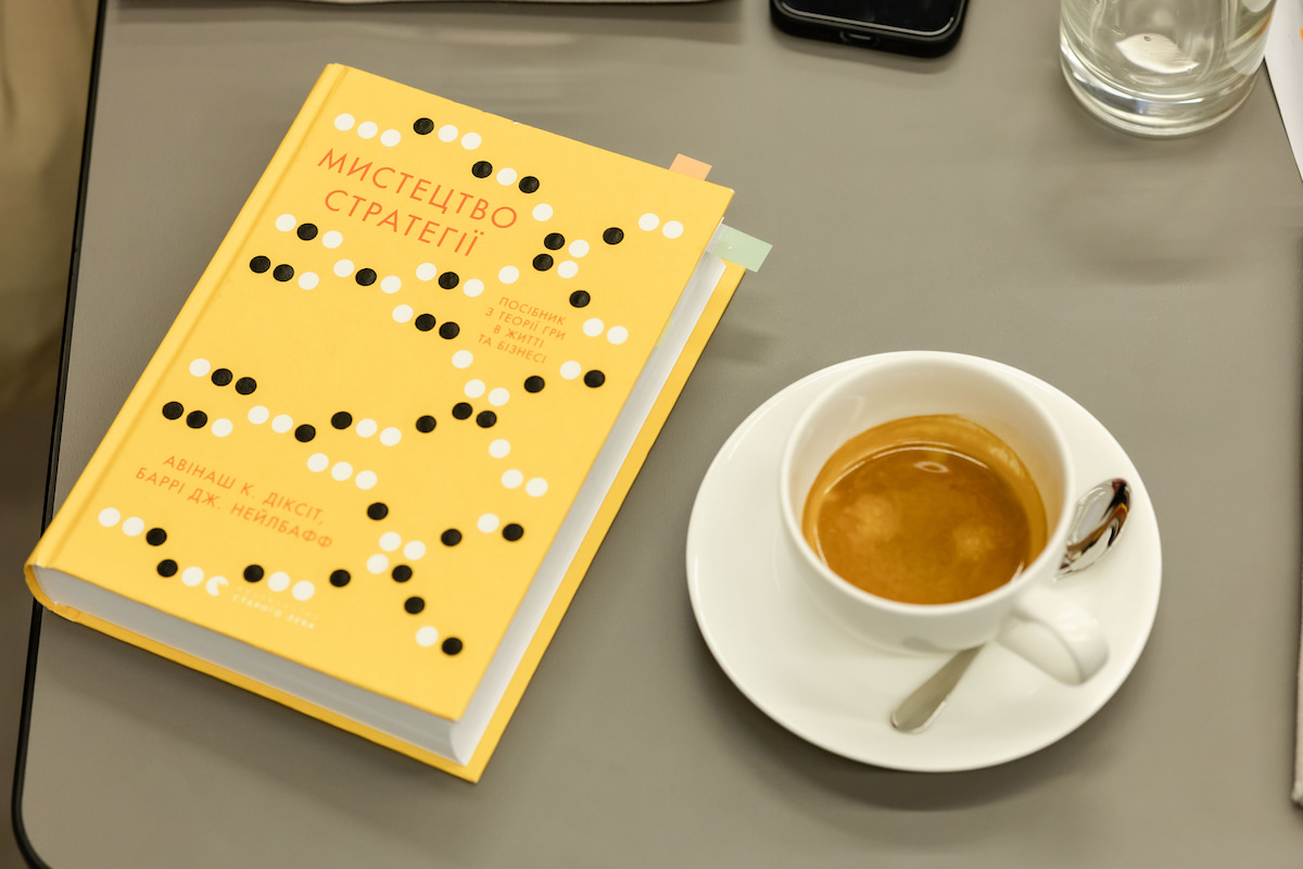 Ukrainian edition of The Art of Strategy beside a cup of coffee at the UCU Business School book club